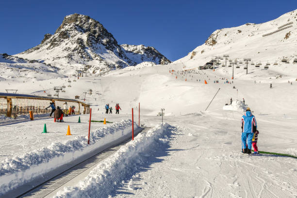 istock Winter resort with children's ski school area with magic carpet conveyor,instructor ans ski slopes between mountains on the background 856420794