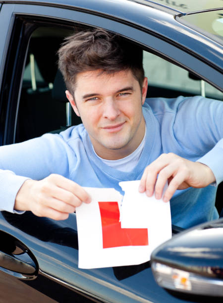istock Happy young male driver tearing up his L sign 856427674