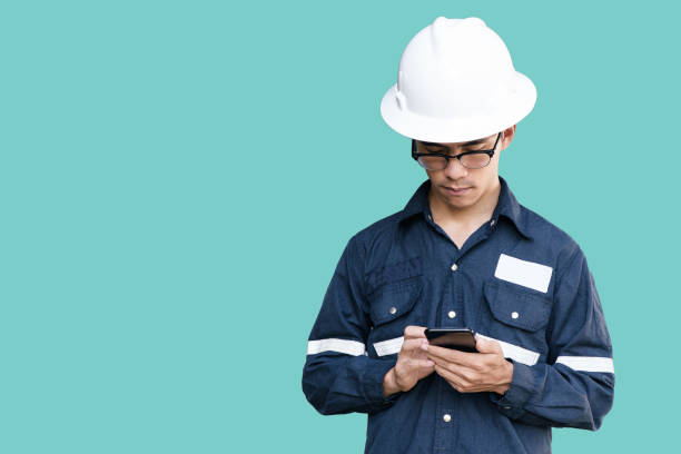 istock Asian man,Engineer or Technician in white helmet, glasses and blue working shirt suit holding smart phone, isolated on green, mechanic and Oil and Gas industrial concept with clipping path. 856427774