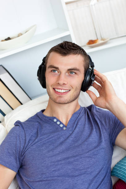 istock Lively young man listening to music sitting on the couch 856428306