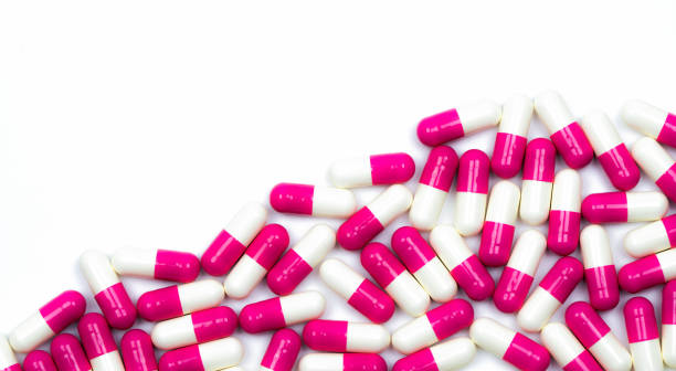 colorful de comprimés antibiotiques pilules isolé sur fond blanc avec espace de copie. résistance aux médicaments, antibiotique utilisation raisonnable, politique de santé et concept de l’assurance maladie. - pink pill photos et images de collection
