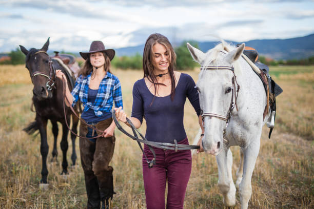 cow-girls sur le terrain avec des chevaux - bride women standing beauty in nature photos et images de collection