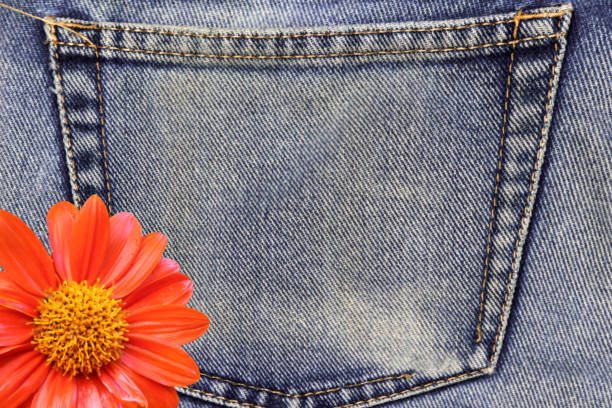 istock Orange flowers in back pocket of blue jean texture. 856435090