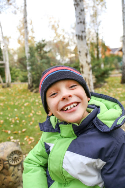 istock A funny  toddler boy in a warm jacket and hat laughing at garden 856435424