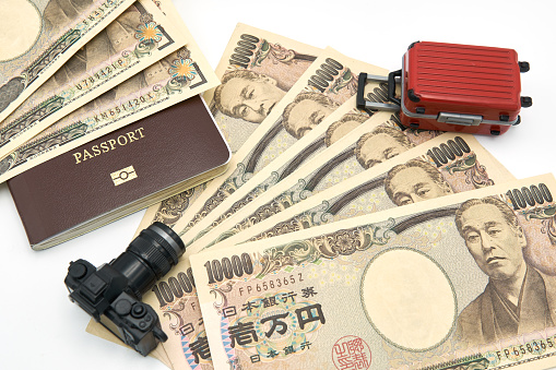 Camera model Red luggage model passport And 10000 yen banknotes placed on a white background. Communicates travel planning to Japan.