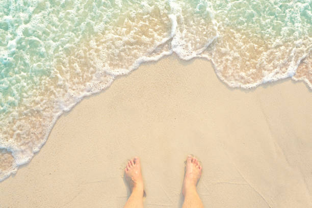 debout pieds nus sur la plage de sable l’eau claire blanc et j’ai de mes pieds à l’île de phuket en thaïlande - flip flop human foot sand women photos et images de collection