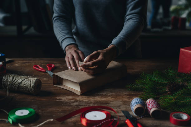 istock woman wrapping book as christmas gift 856441158