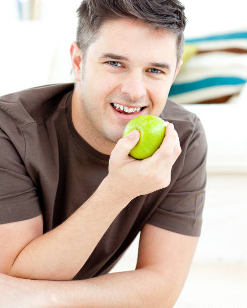 istock Smiling man holding an apple looking at the camera 856441168