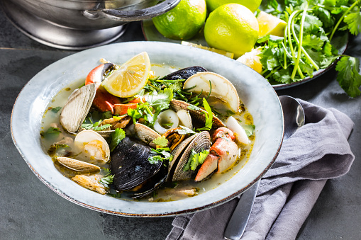 Seafood soup with crabs, clams and mussels. Slate background