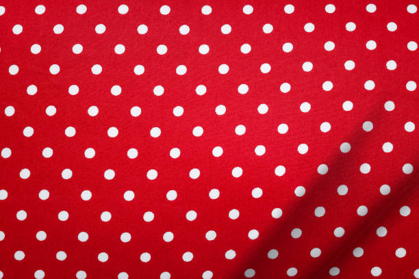 Red fabric in polka dots pattern background. Modern textile texture. Detail of clothing. Christmas concept.