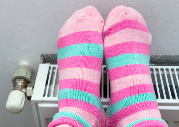 istock Woman warming up feet on radiator at home 856457146