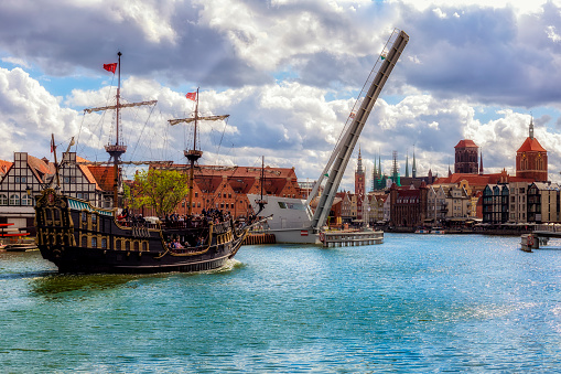 The classic view of Gdansk Old Town with the Hanseatic-style buildings and tourist sailing ship transports tourists across the River Motlawa to the Baltic Sea for a cruise, Poland