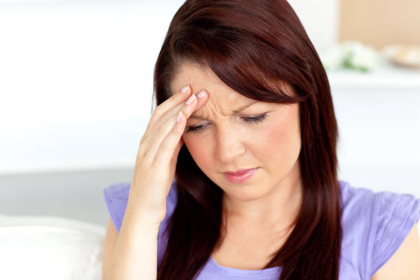 istock Woman with a headache sitting on a sofa at home 856477130