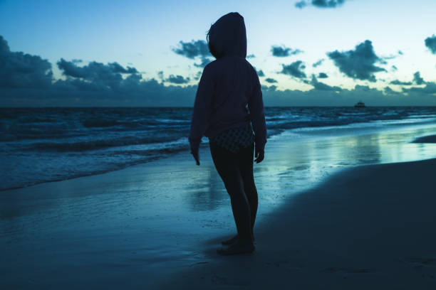 istock Little girl standing on ocean coast in dark 856477278
