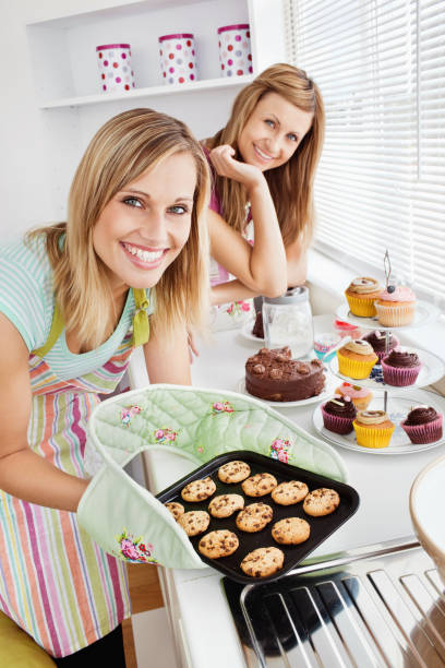 istock Happy female friends holding cookies in the kitchen 856489410