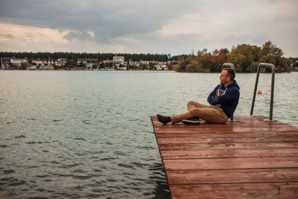 istock Man sitting in a wooden dock pier 856508490
