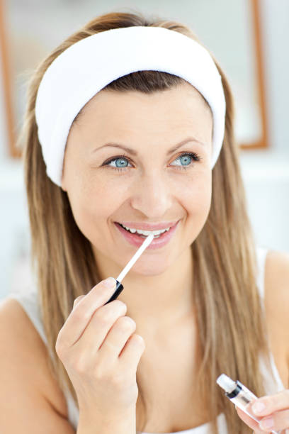 istock Glowing woman applying gloss on her lips in the bathroom 856526006