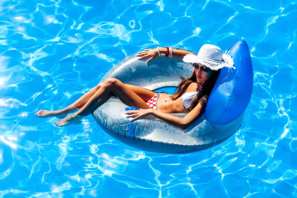 jovem mulher bonita relaxante na piscina. - swimming tube inflatable circle - fotografias e filmes do acervo