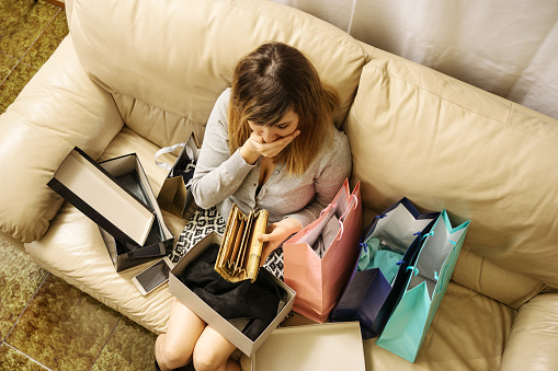 shopping addicted young woman left with no money looks worried for cashless wallet