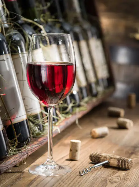 Photo of Wine bottles on the wooden shelf.