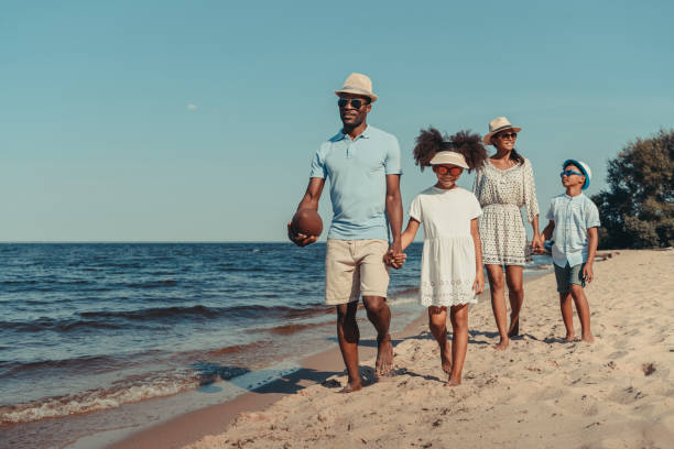 african american family walking on beach beautiful smiling african american family with rugby ball walking together on sandy beach the black womens expo stock pictures, royalty-free photos & images