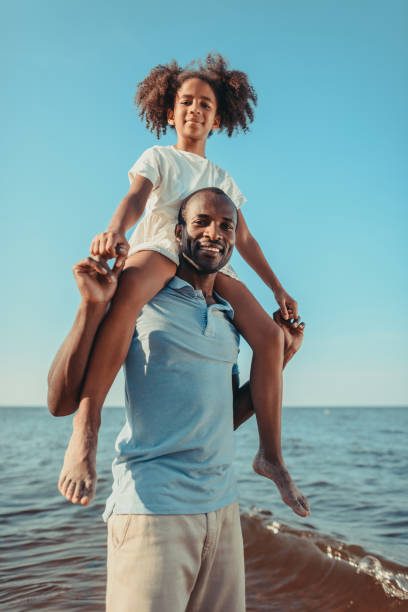 istock african american father carrying daughter on beach 856536588