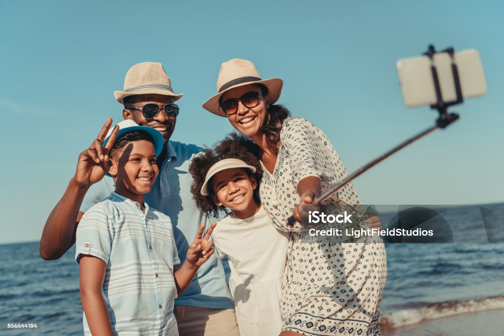 family taking selfie on beach happy african american family taking selfie with smartphone on beach Family Stock Photo