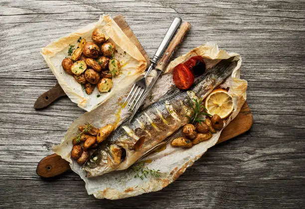 Baked sea bass with roasted potatoes on wooden table