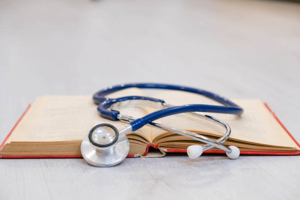 istock Beautiful stethoscope lying on a reference books. Stethoscope with open book on wooden background. Medical literature concept. copy space for text, selective focus 856549010