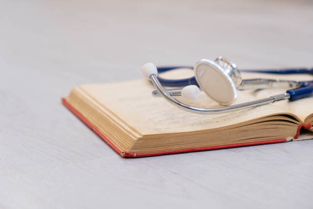 istock Beautiful stethoscope lying on a reference books. Stethoscope with open book on wooden background. Medical literature concept. copy space for text, selective focus 856549068