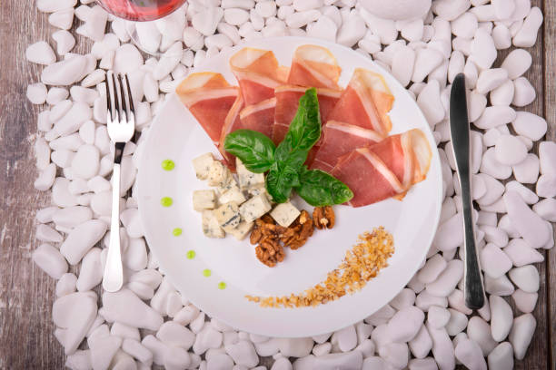 istock Top view of salted prosciutto or balyk, nuts, blue cheese on a white stone background. Expensive food. Business lunch. 856559680