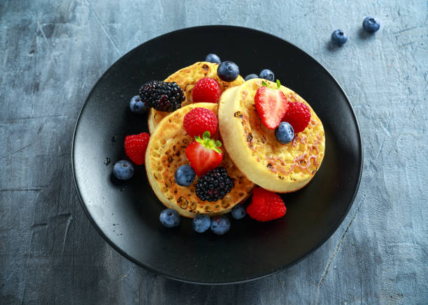 istock British Crumpets breakfast with blueberries, strawberries, blackberries, raspberries drizzled with icing sugar 856560568