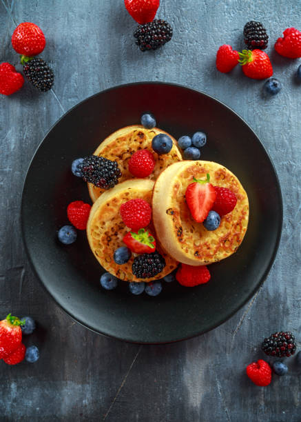 istock British Crumpets breakfast with blueberries, strawberries, blackberries, raspberries drizzled with icing sugar 856560610