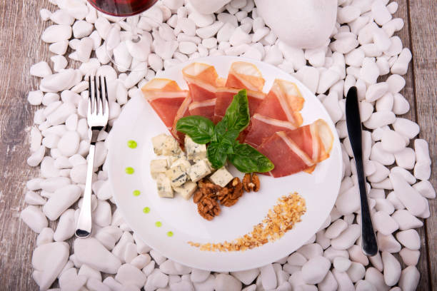 istock Top view of salted prosciutto or balyk, nuts, blue cheese on a white stone background. Expensive food. Business lunch. 856561876