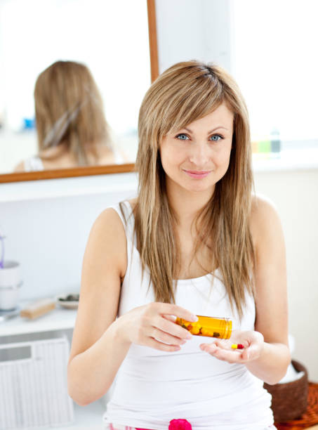 istock Blond woman taking pills looking at the camera in the bathroom 856565008