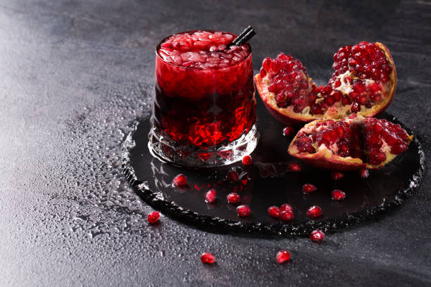 istock A ripe red garnet cut in pieces on a dark gray background. Freshly squeezed pomegranate drink with a black straw. 856568280