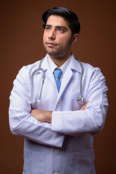 istock Studio shot of young handsome Iranian man doctor against colored background 856571824