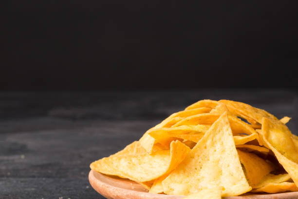 istock Crispy cheese nachos on a a light wooden round plate. Delicious corn chips on a black background. Copy space. 856574866