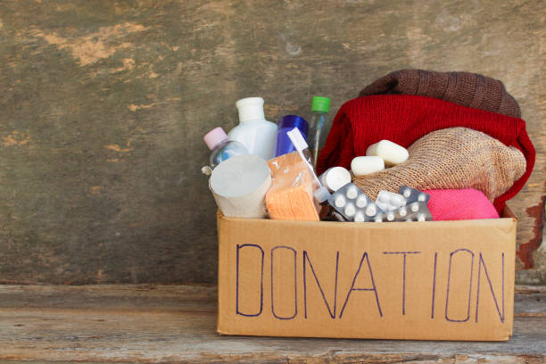 spendenbox mit kleidung, living essentials - spendenbüchse stock-fotos und bilder