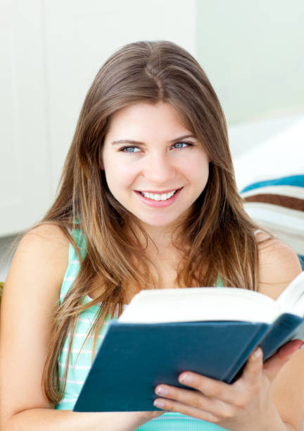 istock Bright woman reading a book sitting on a sofa 856578688