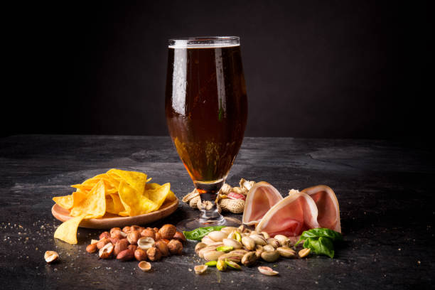 istock Beer and salty snacks on a black background. Alcoholic drink with nuts and chips. Traditional snacks. Copy space. 856578900