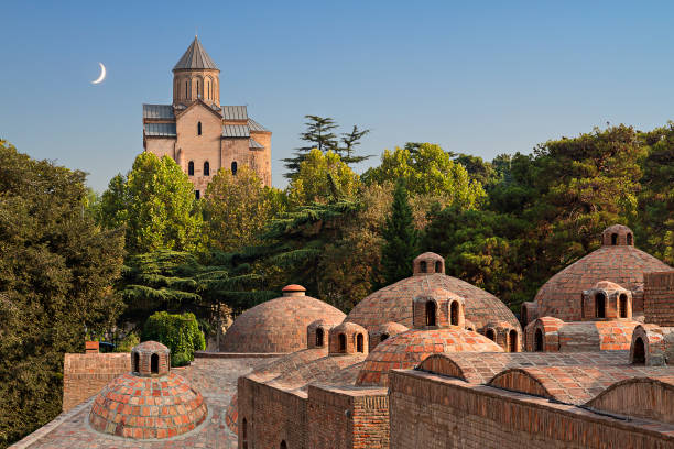 Domes of sulphur baths and Metekhi Church with crescent moon in the sky in Tbilisi, Georgia. View over Metekhi Church with the domes of sulphur baths in the foreground, in Tbilisi, Georgia. ancient arch architecture brick stock pictures, royalty-free photos & images