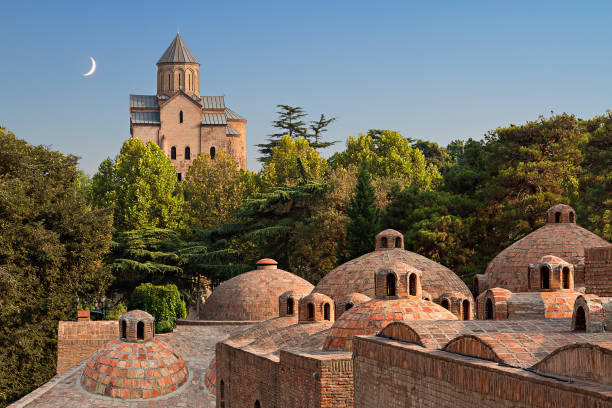 куполы серных ванн и церковь метехи с полумесяцем в небе в тбилиси, г�рузия. - tbilisi стоковые фото и изображения
