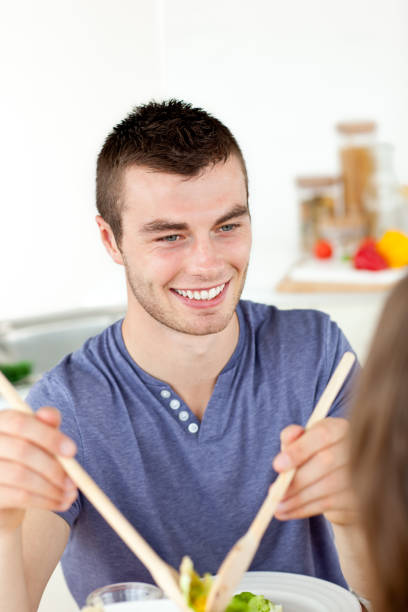istock Happy man putting salad on a plate having dinner with his girlfriend in the kitchen 856586336