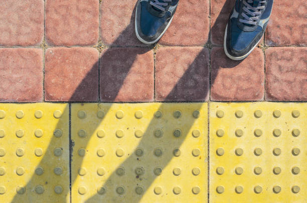 sneakers bleus sur jaune pavés tactiles - yellow color image textured sensory perception photos et images de collection