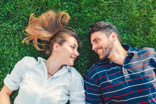 Young couple face to face lying down in the grass