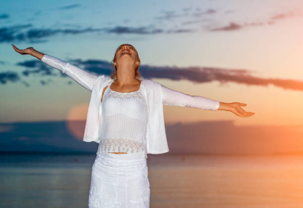 istock Cheering woman open arms under sunrise on beach 856628378