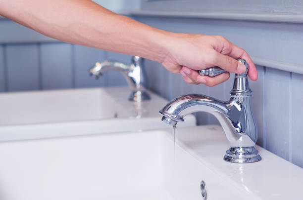 hand man otwarcie baterii srebrnej lub kranu wody z białym umywalką w publicznej toalecie. - heat leak zdjęcia i obrazy z banku zdjęć