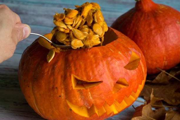 istock Gets a spoonful of pumpkin seeds from Jack's lantern (pumpkins for Halloween) 856631382