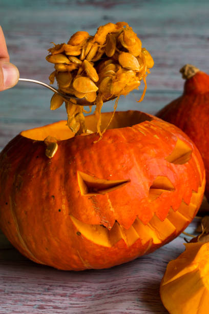 istock Gets a spoonful of pumpkin seeds from Jack's lantern (pumpkins for Halloween) 856631634